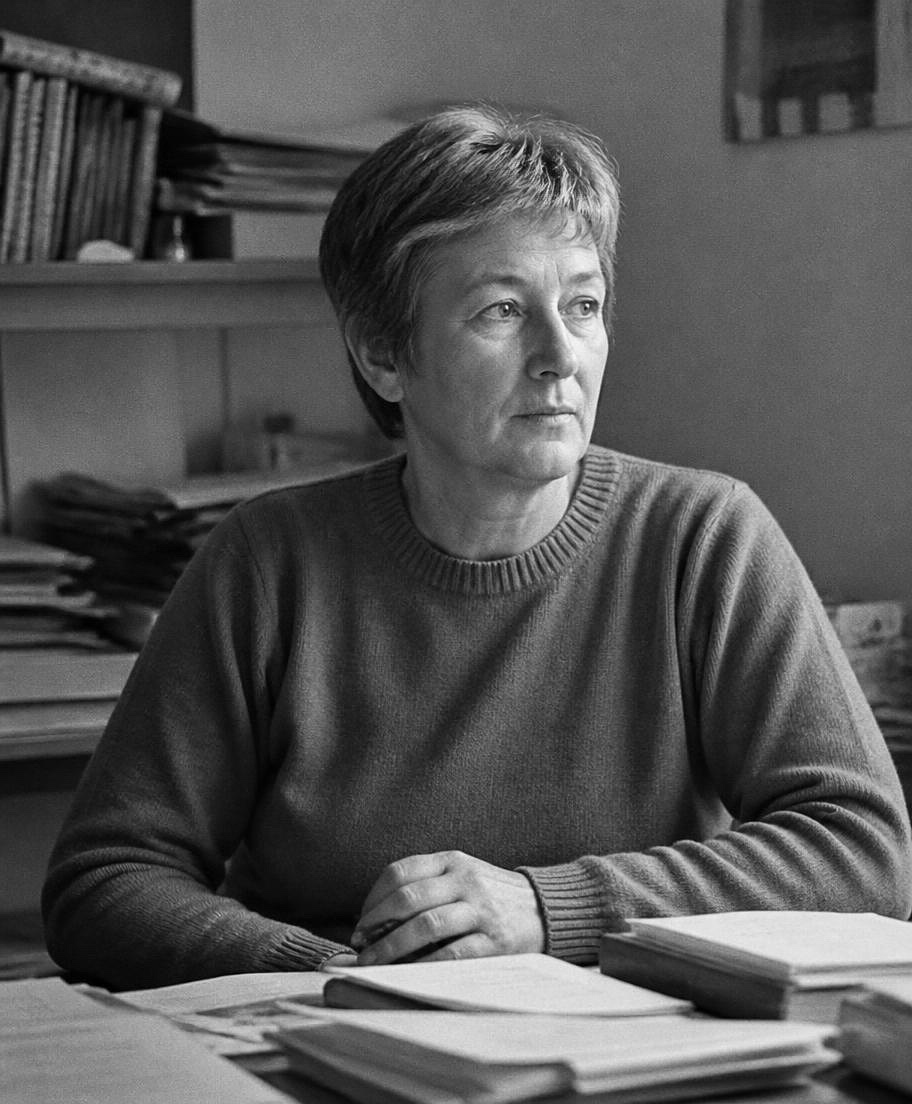 Black-and-white portrait of Eleanor Vale seated at a desk among papers, looking away from the camera.